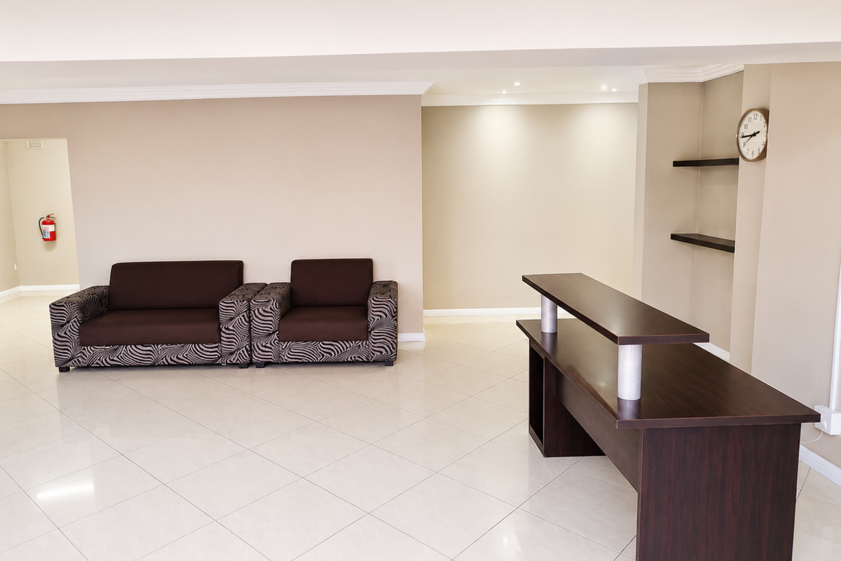 A spacious living area featuring neutral walls, tiled flooring, recessed lighting, and built-in shelving, providing a clean and functional space.