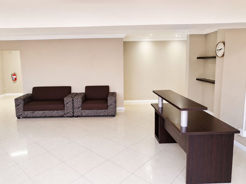 A spacious living area featuring neutral walls, tiled flooring, recessed lighting, and built-in shelving, providing a clean and functional space.