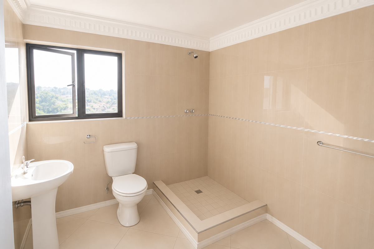 A clean, neutral-toned bathroom featuring a pedestal basin, toilet, and a walk-in shower with tiled finishes and crown molding.