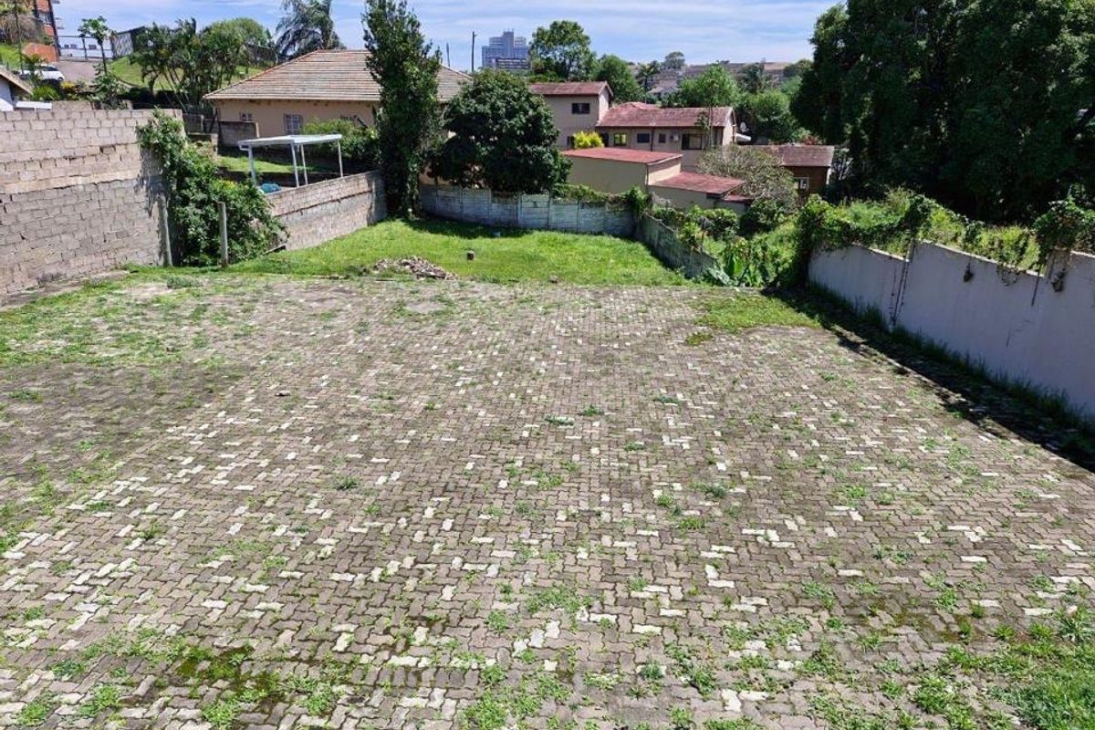 A spacious rear outdoor area featuring extensive paved surfacing and perimeter boundary walls, offering potential for landscaping or development.