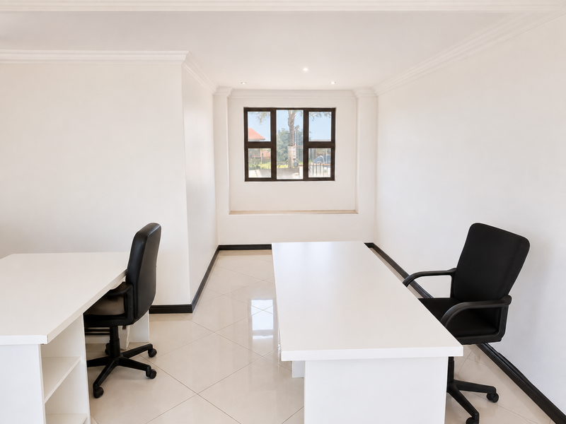 A bright, neutral office space featuring tiled flooring, recessed downlighting, and clean white walls, suitable for a professional workspace.