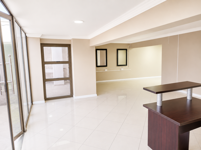 Spacious open-plan interior featuring neutral tiled flooring, recessed lighting, crown molding, and large glass doors providing ample natural light.