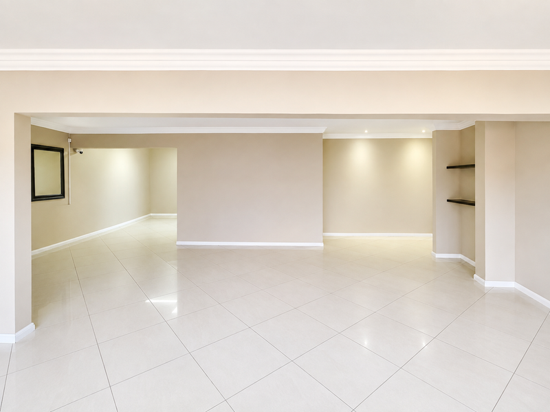 Spacious open-plan living area featuring neutral walls, polished porcelain floor tiles, recessed downlighting, and built-in shelving.