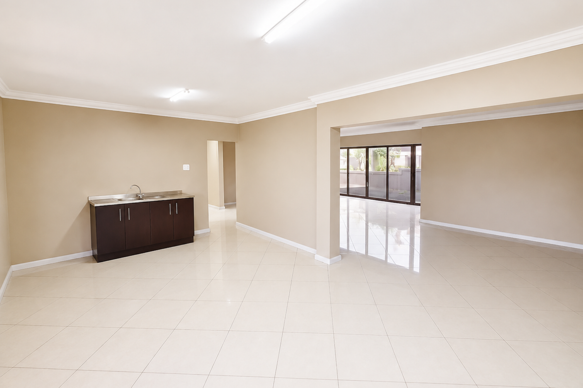 Spacious open-plan living area featuring neutral tiled flooring, built-in cabinetry with a sink, and large sliding glass doors leading to the exterior.