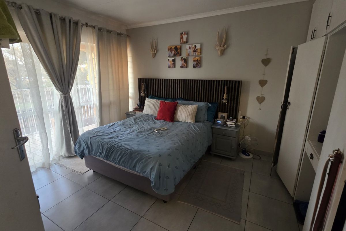 A bedroom featuring tiled flooring, built-in cupboards, and a sliding glass door providing access to an outdoor area.