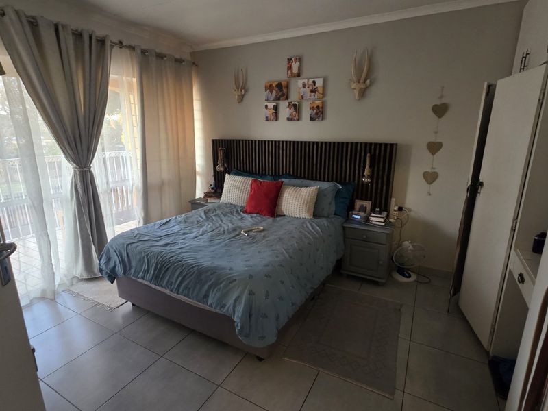 A bedroom featuring tiled flooring, built-in cupboards, and a sliding glass door providing access to an outdoor area.