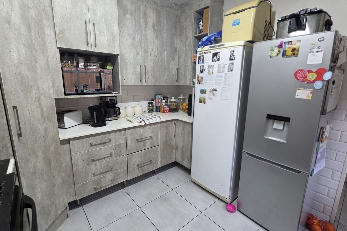 A functional kitchen featuring modern grey wood-look cabinetry, subway tile backsplash, and tiled flooring with ample storage space.