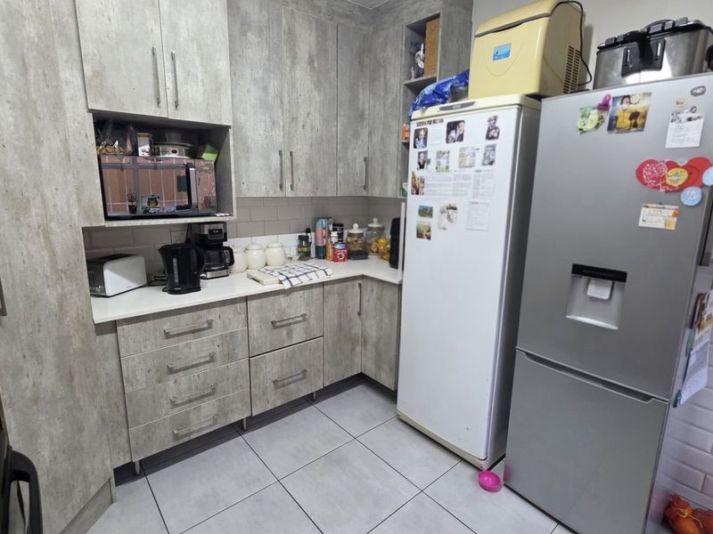 A functional kitchen featuring modern grey wood-look cabinetry, subway tile backsplash, and tiled flooring with ample storage space.