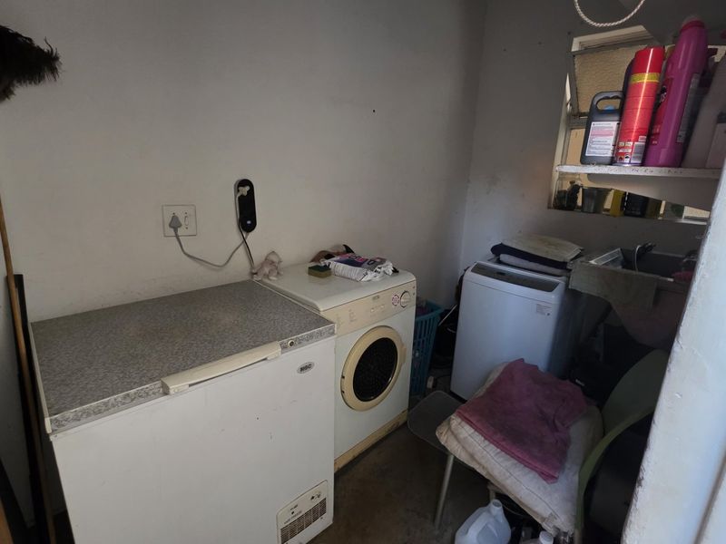 A functional laundry area featuring a sink, plumbing connections, and space for appliances, requiring cosmetic updates to improve the overall condition.