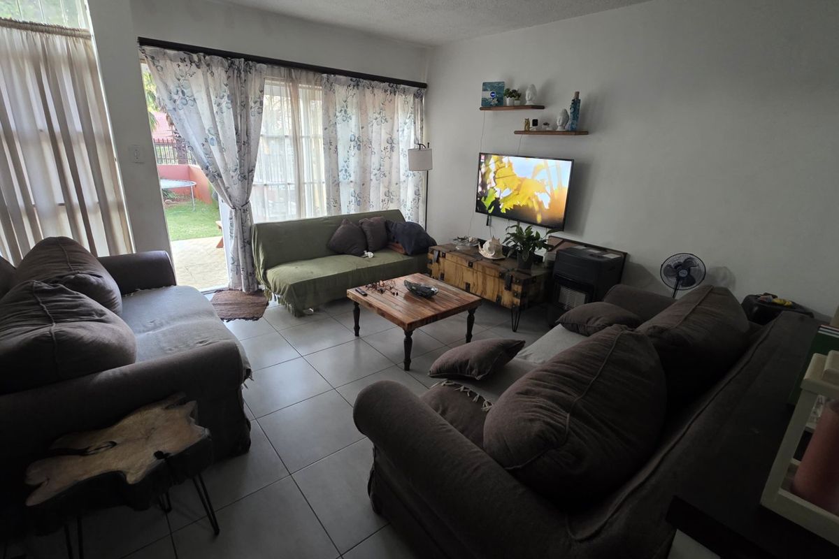 A comfortable living room featuring tiled flooring and a large sliding glass door that provides natural light and access to the outdoor area.