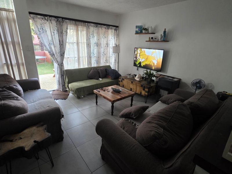 A comfortable living room featuring tiled flooring and a large sliding glass door that provides natural light and access to the outdoor area.