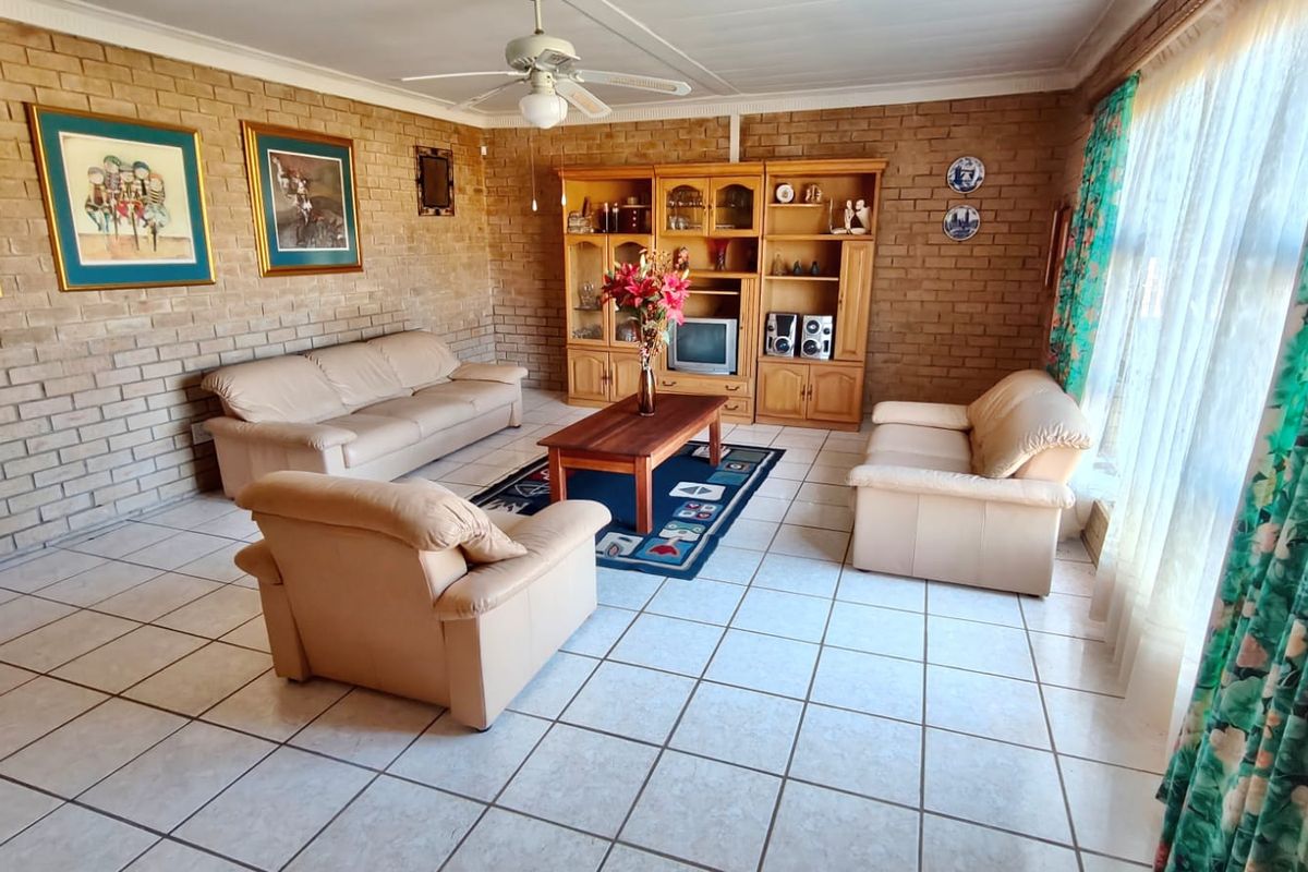 Spacious living room featuring exposed brick walls, tiled flooring, and a ceiling fan, offering a classic, dated aesthetic ready for modernization.