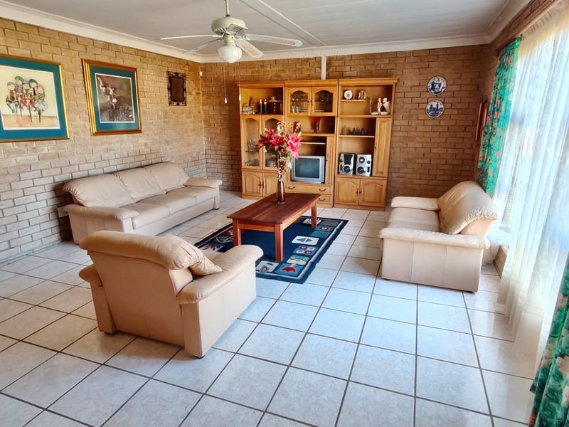 Spacious living room featuring exposed brick walls, tiled flooring, and a ceiling fan, offering a classic, dated aesthetic ready for modernization.
