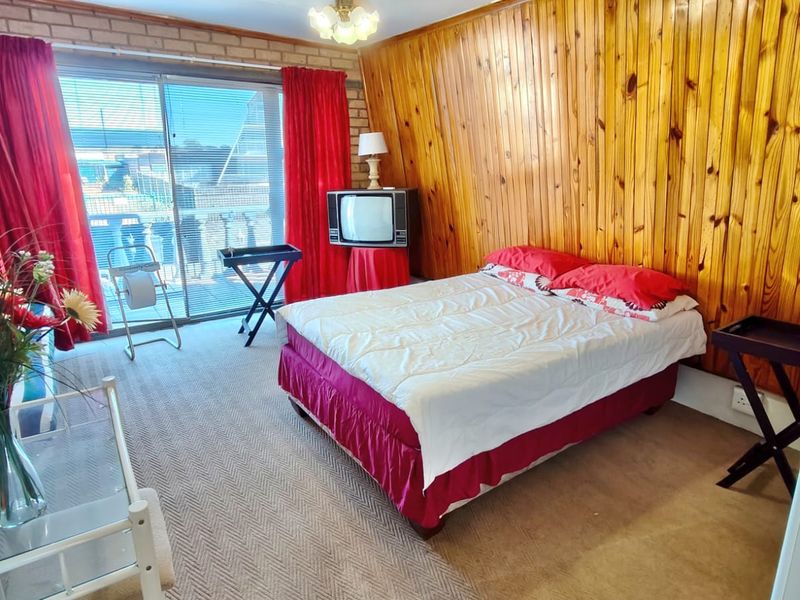 A bedroom featuring timber wall paneling, exposed brickwork, and a sliding glass door providing access to an outdoor area.