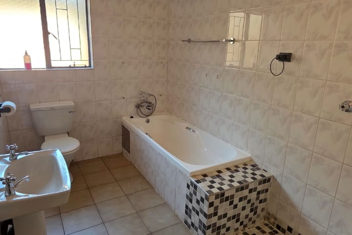 A functional bathroom featuring a pedestal basin, bathtub, and a separate shower area with tiled finishes throughout.