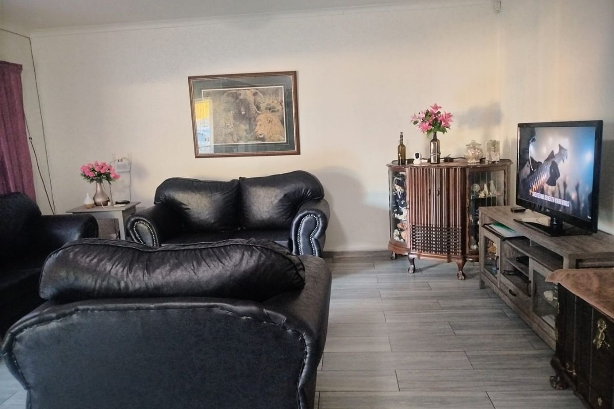 A comfortable living room featuring modern grey wood-look floor tiles and neutral wall finishes, providing a functional and well-maintained space.