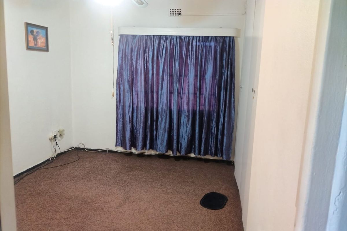 An empty bedroom featuring carpet flooring, a ceiling fan, and built-in storage cupboards.
