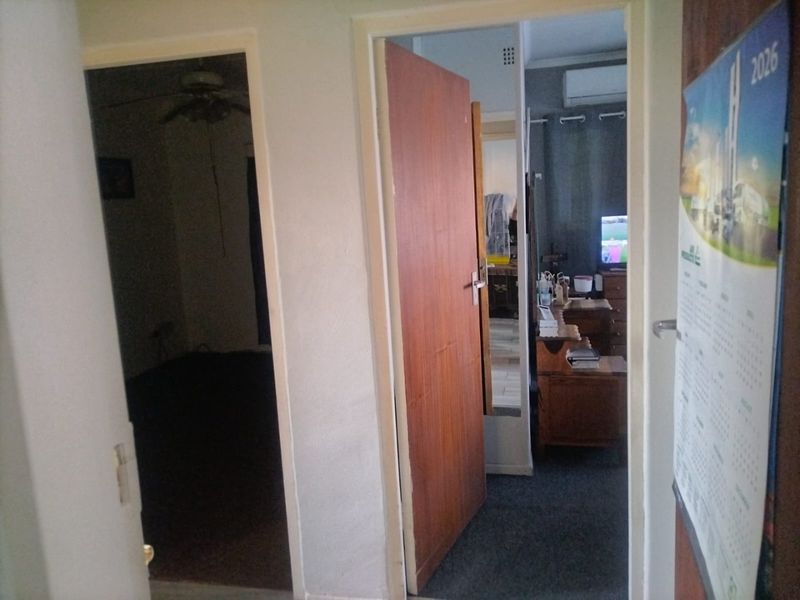 A view through a hallway connecting multiple rooms, featuring standard internal doors and neutral wall finishes.