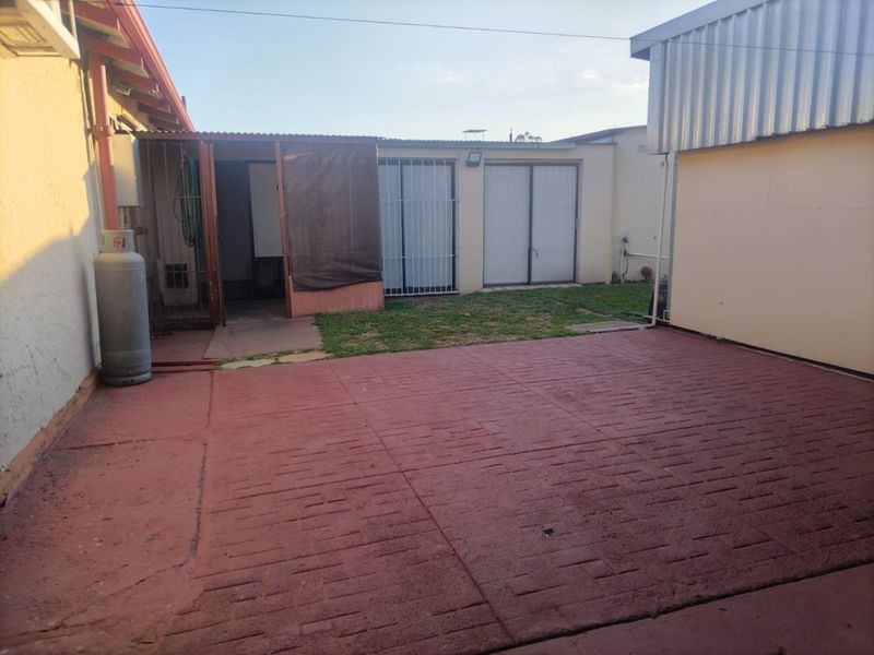 Rear exterior area featuring a paved patio, security gates, and sliding door access to the main dwelling.
