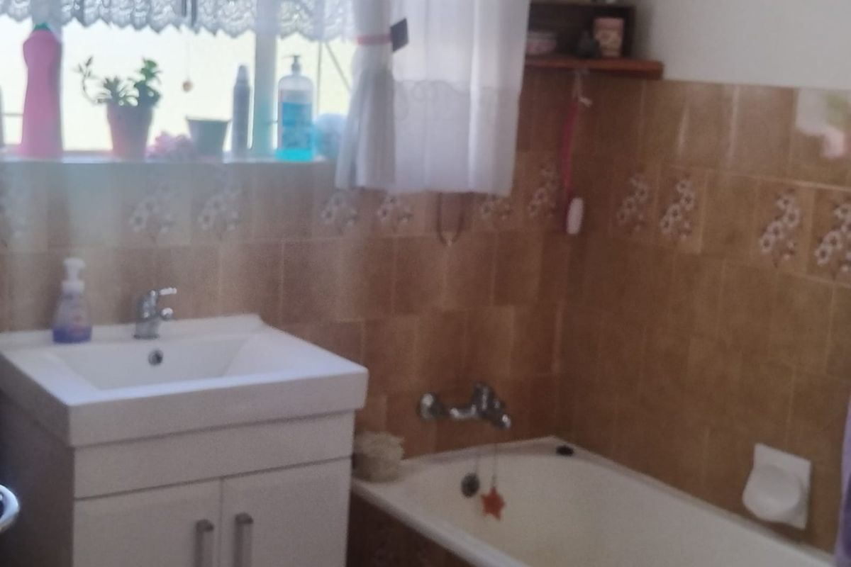 A functional bathroom featuring a vanity cabinet with basin, a bathtub, and tiled walls.