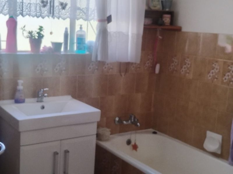 A functional bathroom featuring a vanity cabinet with basin, a bathtub, and tiled walls.