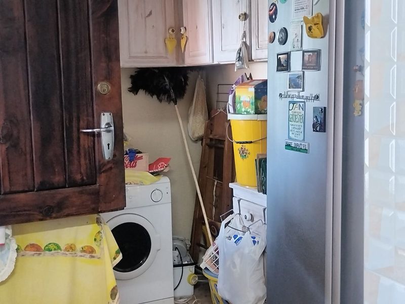 A compact laundry area featuring built-in cabinetry and space for a washing machine, currently used for utility storage.