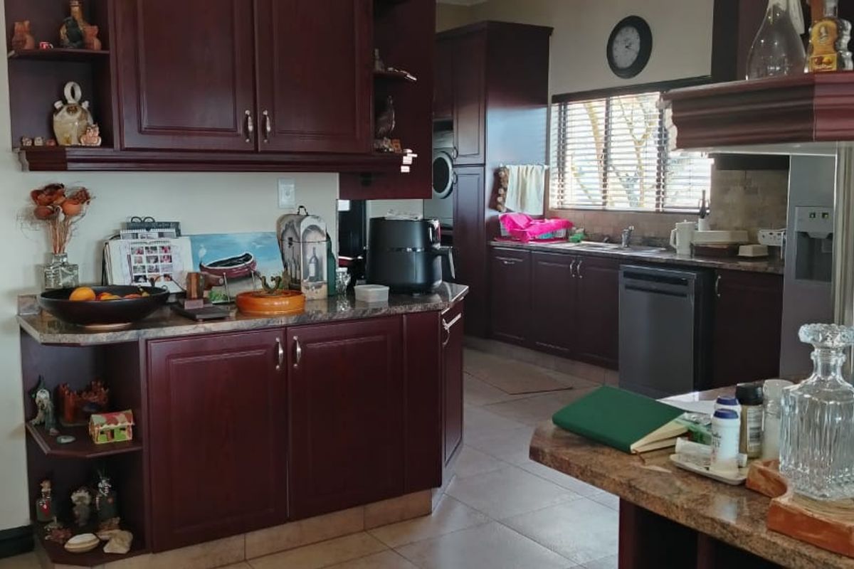 A functional kitchen featuring dark wood cabinetry, granite countertops, tiled flooring, and integrated appliances, offering a traditional aesthetic with ample storage space.