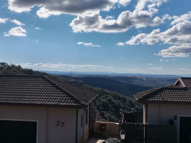 Elevated view overlooking the townhouse complex rooftops and surrounding landscape under a clear blue sky.