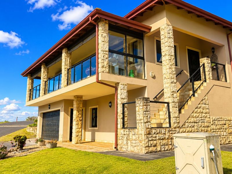A well-maintained townhouse exterior featuring stone cladding, a spacious upper-level balcony with glass balustrades, and an integrated garage.