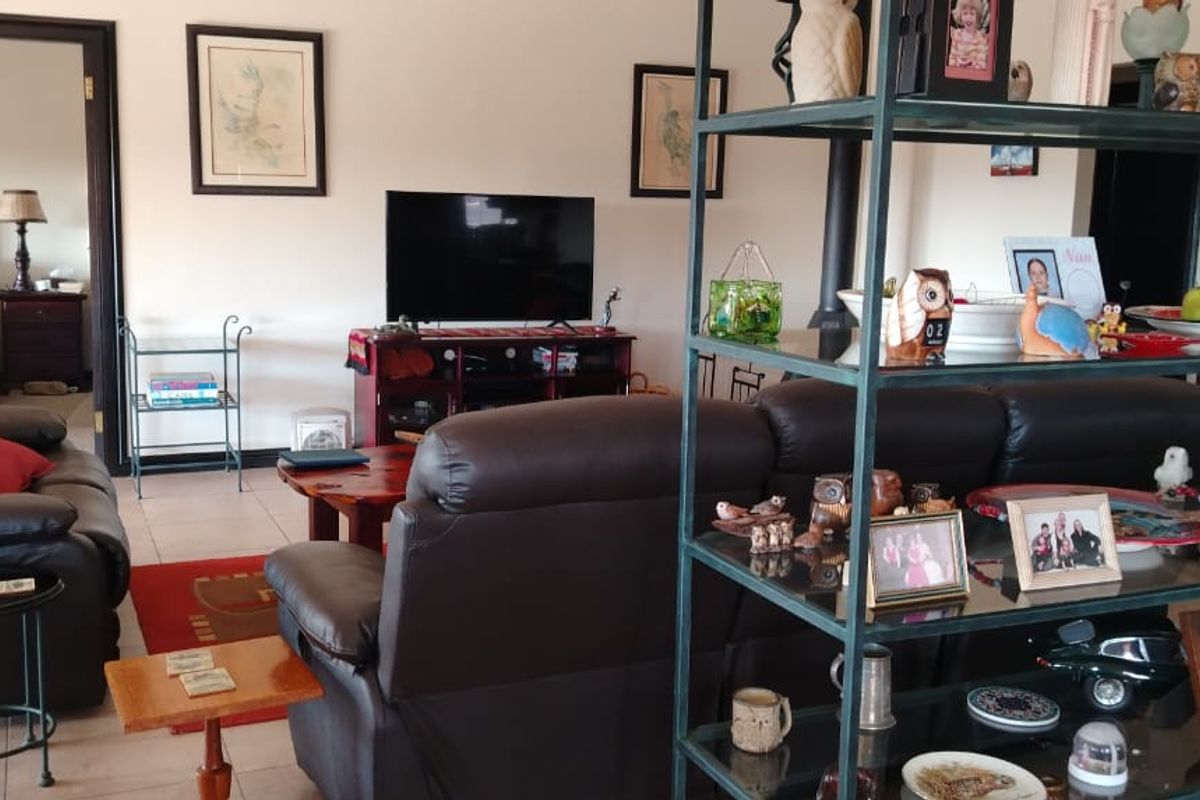 A spacious living room featuring tiled flooring and dark wood door frames, providing a functional and comfortable central living area.