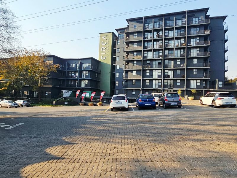 Exterior view of the Circa Lynnwood apartment complex featuring a multi-story building facade with balconies and an adjacent paved parking area.