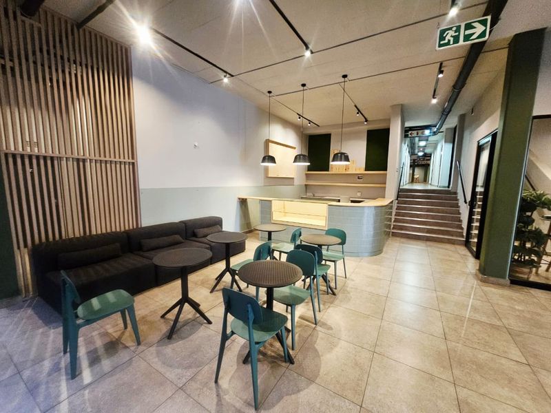 Modern open-plan communal area featuring tiled flooring, a built-in service counter, timber slat wall detailing, and recessed track lighting.