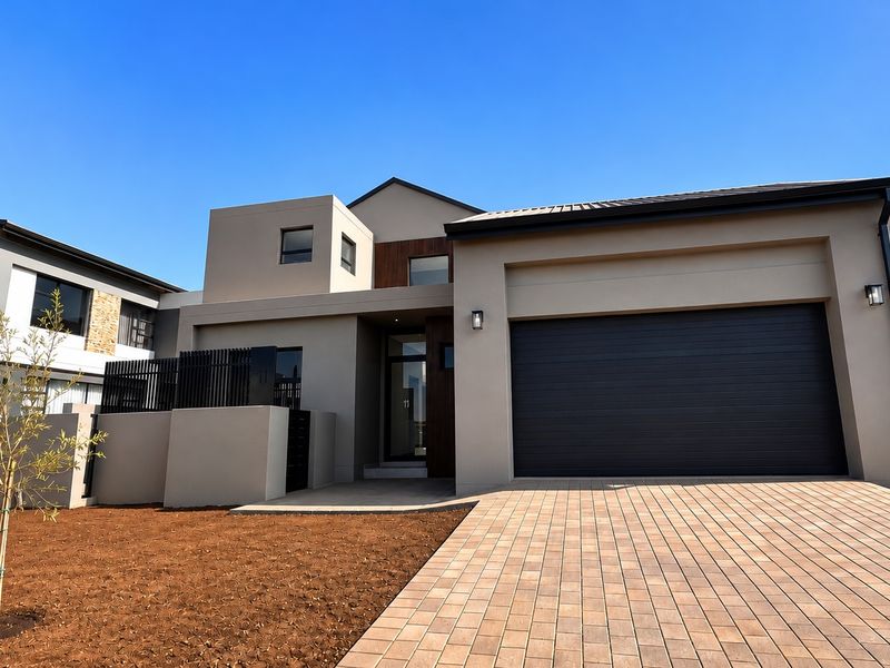 Modern double-story residential facade featuring a paved driveway, integrated double garage, and contemporary architectural design with clean lines and neutral tones.
