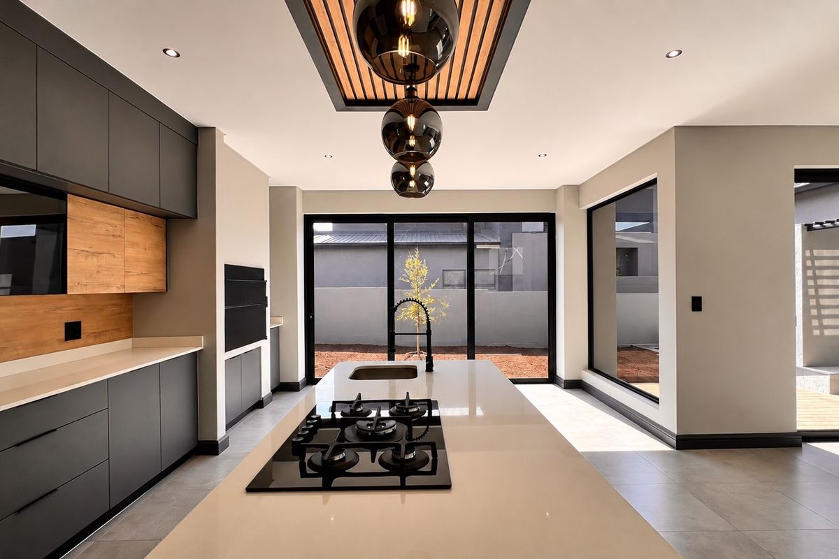Modern, high-end kitchen featuring a central island with gas hob, sleek cabinetry, stone countertops, and a unique timber slat ceiling detail with pendant lighting.