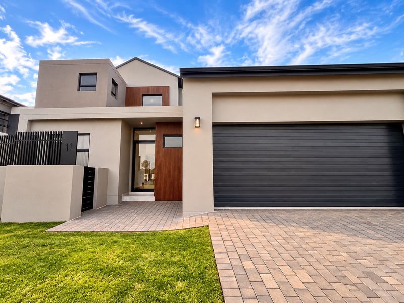 Modern contemporary front facade featuring a double garage, paved driveway, timber accents, and clean architectural lines.