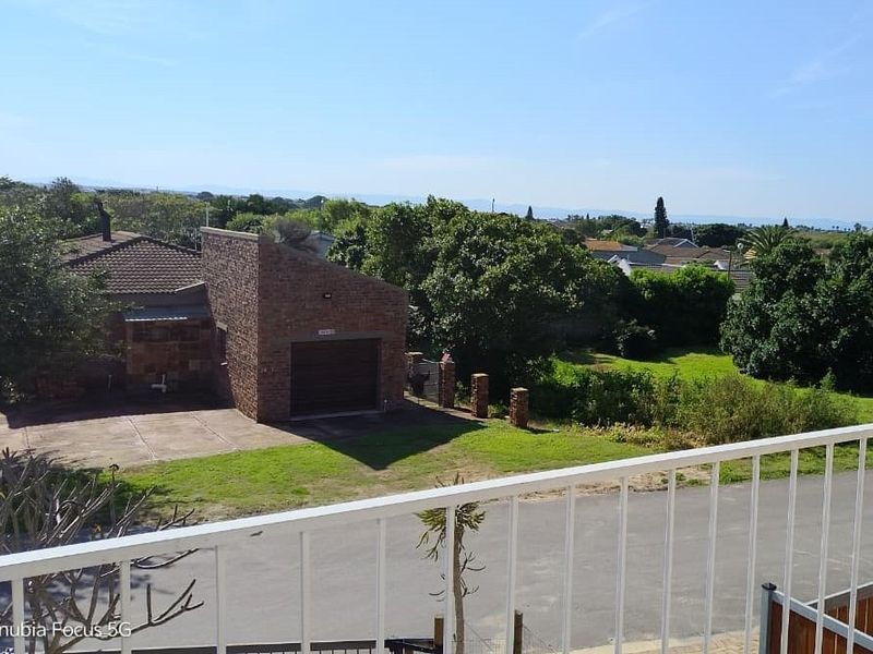 Elevated view overlooking a residential property with a brick garage, paved driveway, and surrounding garden area.
