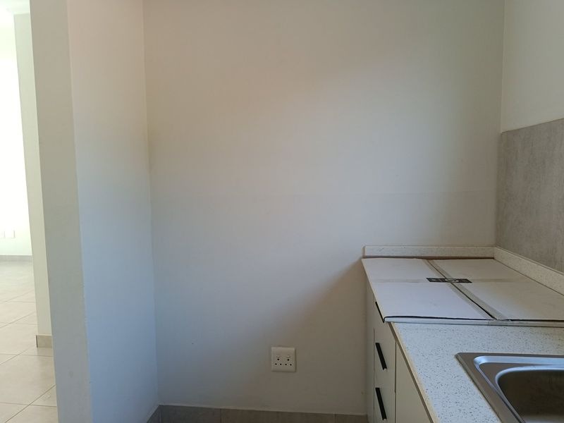 A clean, functional scullery area featuring built-in cabinetry, a stone countertop, and a stainless steel sink, providing additional prep and wash-up space.