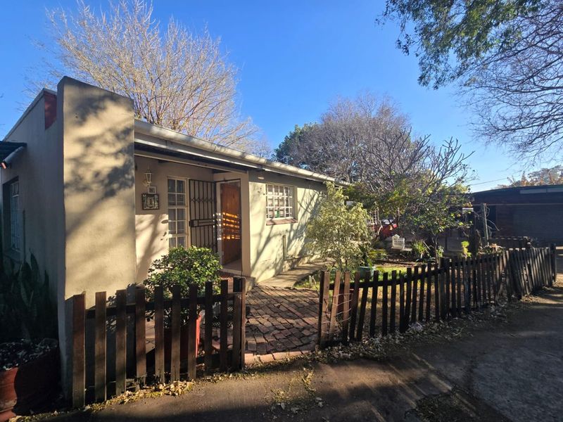 Front exterior view of a single-story house featuring a brick paved entrance path and timber picket fencing.
