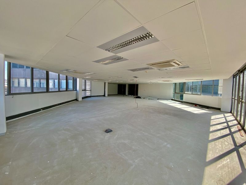 Spacious open-plan commercial office area featuring suspended ceilings, recessed lighting, ducted air conditioning, and large windows providing ample natural light.
