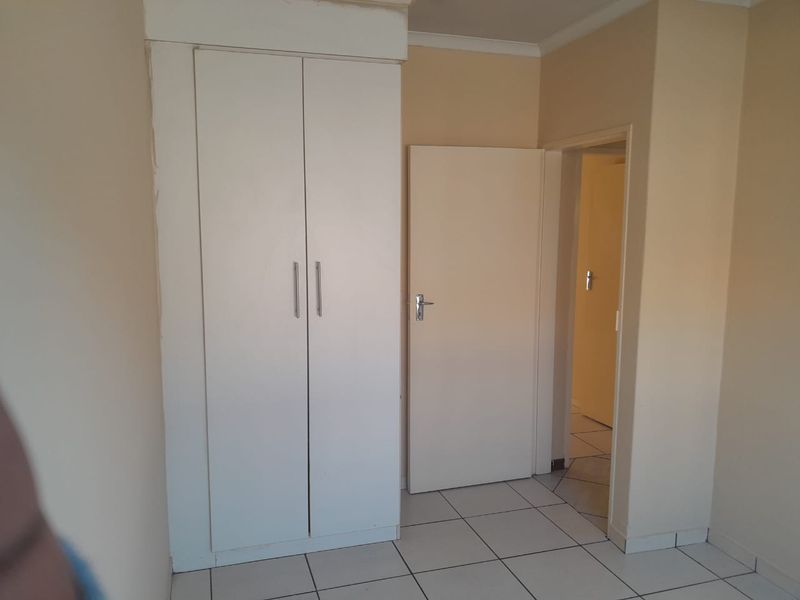 A simple bedroom featuring tiled flooring and a built-in wardrobe, offering a clean, neutral space ready for personalization.