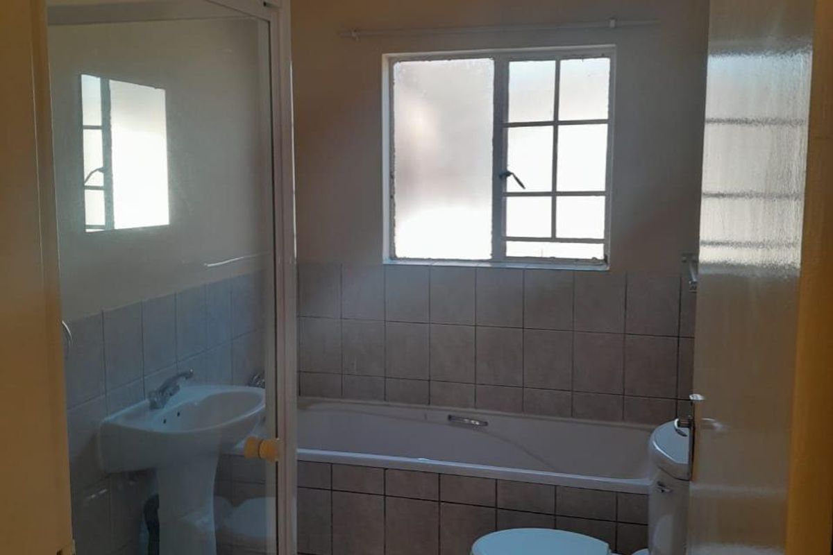 A functional bathroom featuring a pedestal basin, shower enclosure, bathtub, and toilet with tiled finishes throughout.
