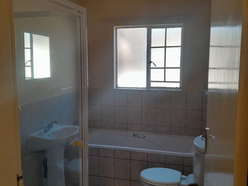 A functional bathroom featuring a pedestal basin, shower enclosure, bathtub, and toilet with tiled finishes throughout.