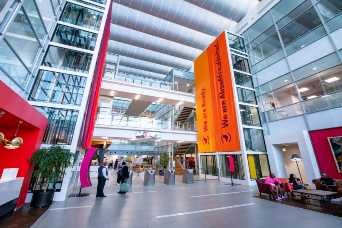 Spacious modern commercial atrium featuring high ceilings, glass elevator shafts, security turnstiles, and large windows providing ample natural light.
