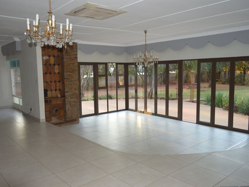 Spacious, empty living area featuring tiled floors, a built-in fireplace, and large glass sliding doors providing direct access to the garden.