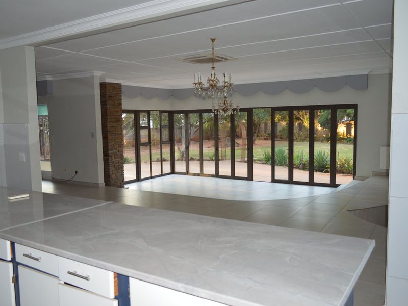 Spacious open-plan living area featuring large folding glass doors that open to the garden, stone-clad pillar, and a modern kitchen island.