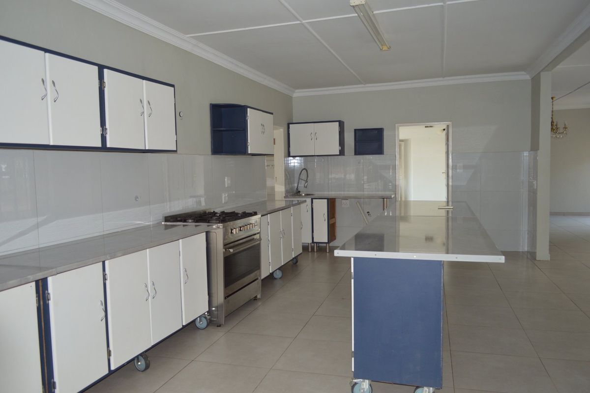 Spacious kitchen featuring built-in cabinetry, a gas stove, stainless steel countertops, and tiled flooring, offering a functional layout ready for modernization.