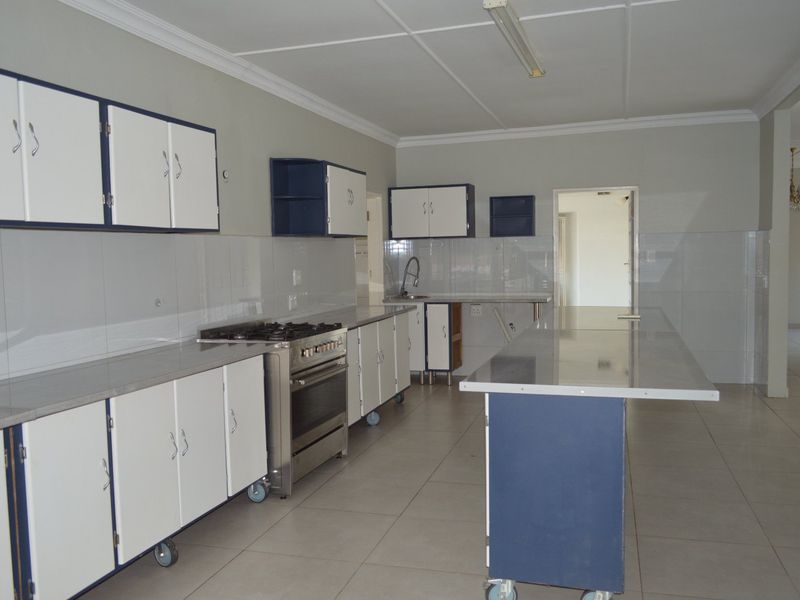 Spacious kitchen featuring built-in cabinetry, a gas stove, stainless steel countertops, and tiled flooring, offering a functional layout ready for modernization.