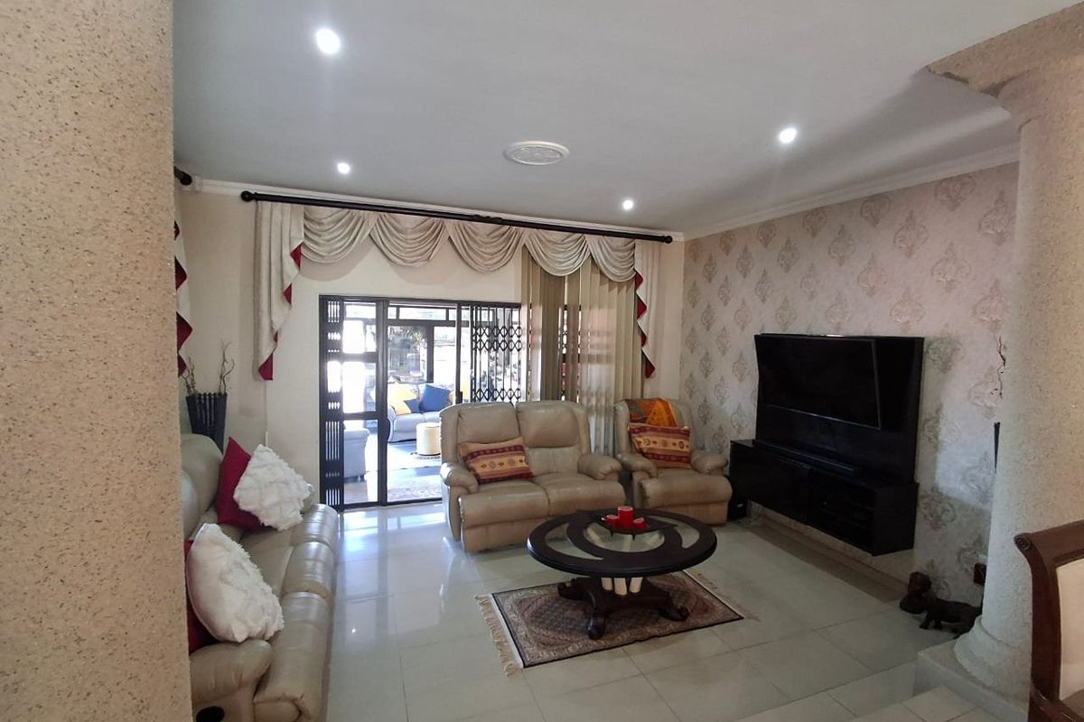 A well-maintained living room featuring tiled floors, recessed lighting, and a decorative column, with direct access to an outdoor patio area.