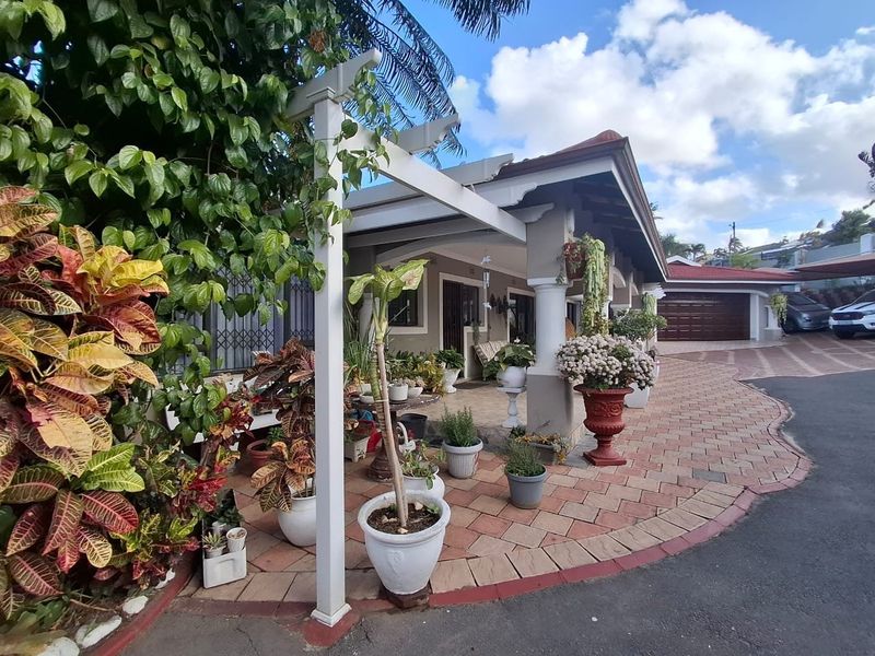 Front exterior view featuring a paved driveway, covered patio area with pergola, and an attached garage.