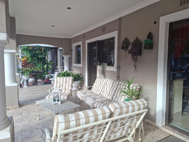 A covered outdoor patio area featuring tiled flooring, recessed lighting, and access to the home through a sliding glass door.